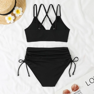 Flat lay of black high-waisted bikini set with drawstring details and beach accessories