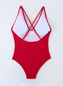 Detail view of red one-piece swimsuit featuring cross-back straps and removable white pads