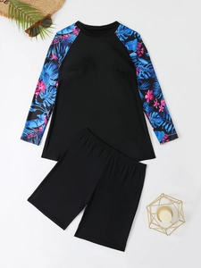 Flat lay of long sleeve tankini top with tropical leaf print and black swim shorts