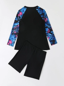 Flat lay of a two-piece long sleeve tankini swimsuit with tropical leaf print and black shorts