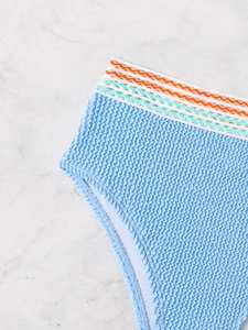 Macro shot of light blue seersucker bikini bottom with colorful wavy embroidered waistband