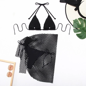 Flat lay of black 3-piece bikini set with mesh cover-up skirt and beach accessories