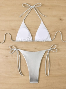 Detailed close-up of a metallic silver bikini with tie straps on a light wood background