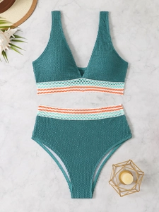 Detailed view of teal seersucker bikini with colorful wavy embroidered bands on marble background