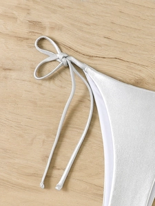Detail of silver metallic bikini bottom with adjustable side ties on wooden background
