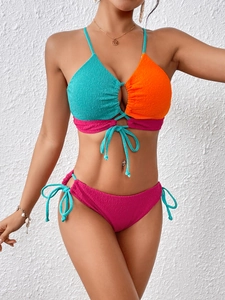 Detail of color-block bikini showing crinkle fabric texture and lace-up ties