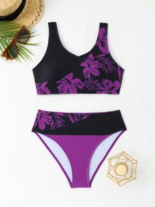 Flat lay of a two-piece bikini with purple floral print and summer beach accessories