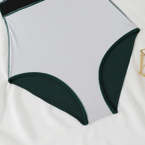 Detail view of white mesh fabric with dark green ribbed edging on one-piece swimsuit