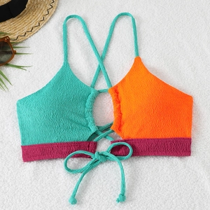 Flat lay of textured seersucker bikini top with color-block straps on a white plush rug