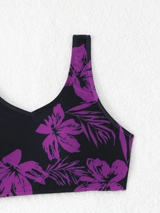 Close-up of black bikini top featuring vibrant purple floral and tropical leaf prints