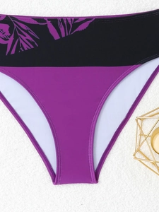 Detail of high-waisted purple bikini bottoms with black tropical leaf printed waistband