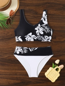 Flat lay of high-waisted bikini set with tropical floral print and vacation accessories