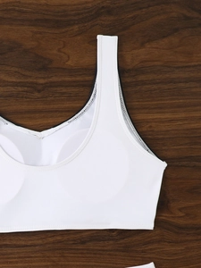 Detail of white sports bikini top with removable pads and wide straps on wood background