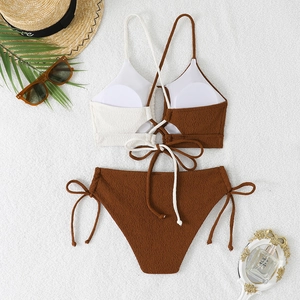 Flat lay of a contrast bikini set with textured fabric, straw hat and sunglasses