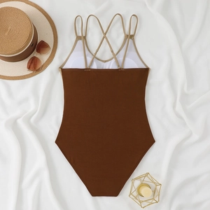 Detail of coffee ribbed one-piece swimsuit with cross straps on white fabric background