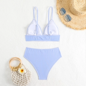 Flat lay of blue and white striped high-waisted bikini with summer beach accessories