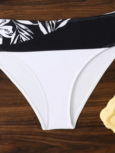 Detail of two-tone bikini bottom with black tropical leaf print and white paneling