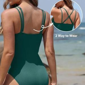 Dark green ribbed one-piece swimsuit with adjustable 2-way straps on beach background
