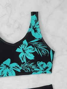 Detail of V-neck bikini top with floral print and reinforced stitching on marble surface