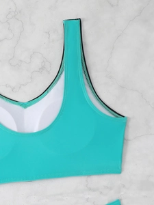 Detail of teal sports bikini top featuring U-neck design and built-in white chest pads