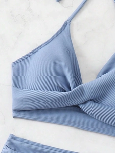 Close-up of light blue ribbed bikini top with cross knot detail on marble background