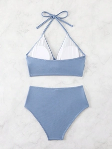 Detail view of Morandi blue ribbed high-waisted bikini with halter top on marble
