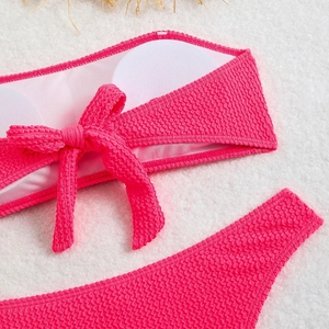 Detail of rose pink bikini featuring puckered texture fabric and front bow with pads