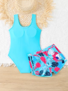 Set bikini da bambina blu con stampa floreale e accessori estivi su sfondo di legno