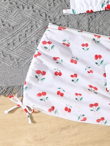 Detailed view of white bikini skirt with red cherry print and side drawstring ties