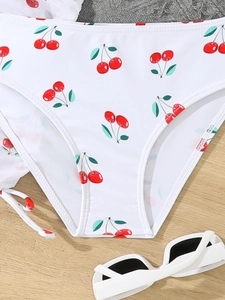 Close-up of white high-waisted bikini bottoms featuring vibrant red cherry prints