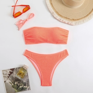 Flat lay of orange strapless bikini with smocked fabric and summer vacation accessories