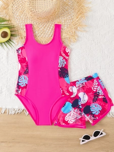 Dettaglio di un costume da bagno due pezzi da ragazza con stampa tropicale e accessori
