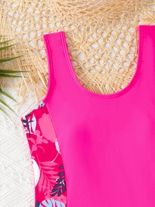 Primo piano di costume da bagno rosa da ragazza con motivi floreali tropicali e palma