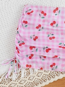Detail of pink plaid skirt with cherry print and adjustable side drawstring for girls