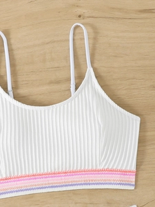 Dettaglio della fascia elastica a righe colorate su un top bikini bianco a coste