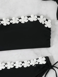 Close-up of black bikini with white lace floral embroidery and pearl bead detailing