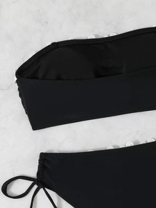 Detailed view of black bikini top with white scalloped lace edges and removable pads