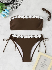 Flat lay of brown two-piece bikini with white floral appliques and bead details
