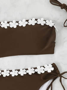 Detail of dark brown bikini with white 3D lace flowers and pearl embellishments