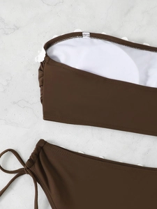 Detail of dark brown bikini top featuring white flower lace trim and round breast pads