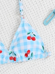 Close-up of sky blue checkered girl bikini with red cherry print and adjustable straps