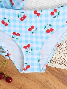 Close-up of girls blue gingham bikini bottoms featuring a cute red cherry print pattern