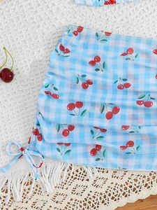 Detail view of light blue gingham bikini with cherry print and side drawstring ties