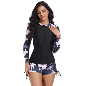 Detailed view of women's long sleeve rash guard with purple lily pattern and side-tie shorts