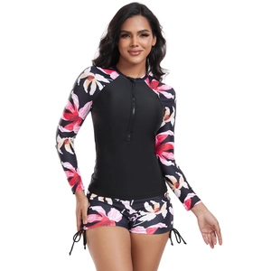 Detail of long sleeve rash guard with floral print, front zipper, and drawstring shorts