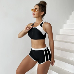 Detail of high-waisted black two-piece sporty bikini with white piping and zipper vest