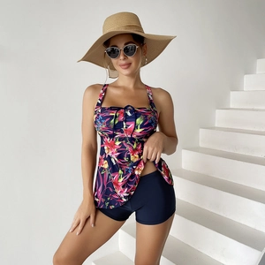 Detail of floral tankini top with navy boy shorts and vibrant tropical print design
