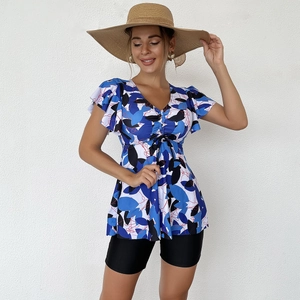 Detail of floral printed tankini top with V-neck and drawstring plus black swim shorts