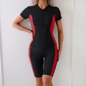 Detail of black and red two-piece short sleeve surf suit with front zipper design