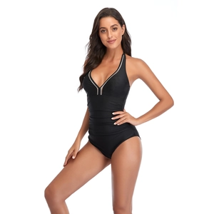 Detail of black one-piece swimsuit with V-neckline, white piping, and ruched tummy control